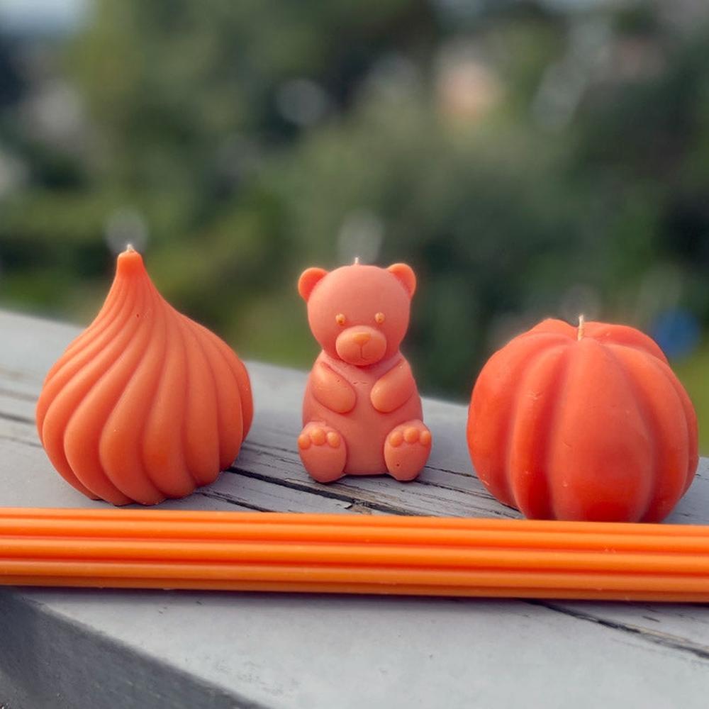 Oransje bamselys, løklys og gresskarlys i soyavoks med veke, samt oransje lyspinner.