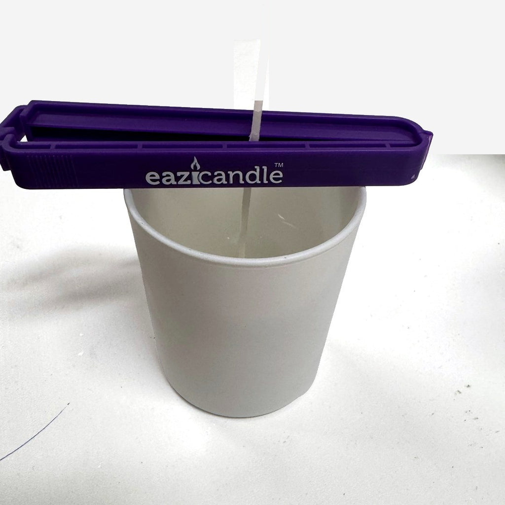 Eazi wick clip holder veken midt i et hvitt lysglass