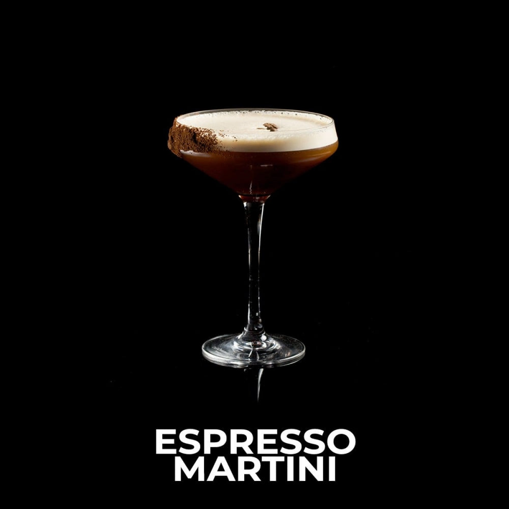 Espresso Martini cocktail i et glass med skum, kaffebønne og sjokoladepulver på kanten, mot svart bakgrunn