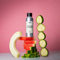 Sølvfarget duftoljeflaske "Melon and Cucumber" på stablede vannmelonskiver, med agurkskiver og melonkant.