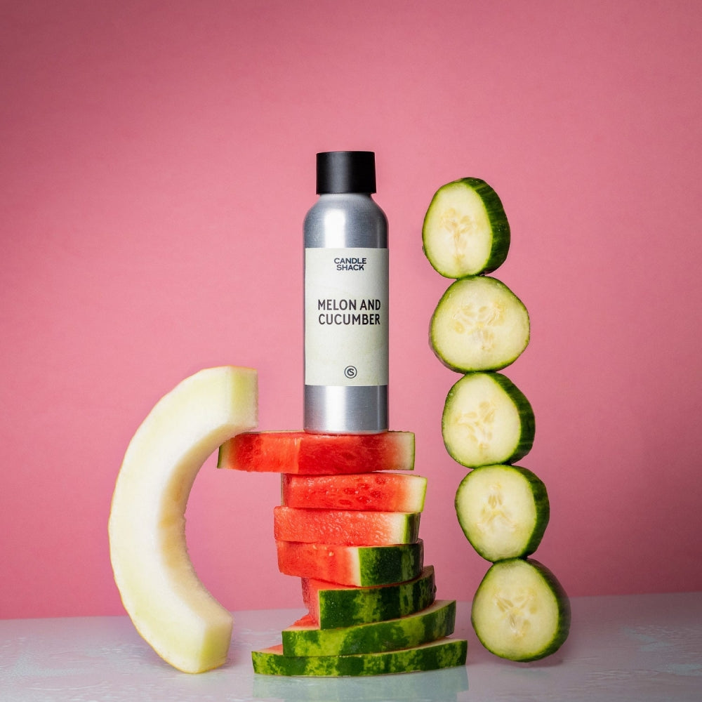 Sølvfarget duftoljeflaske "Melon and Cucumber" på stablede vannmelonskiver, med agurkskiver og melonkant.