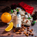 Sølvfarget flaske Nutcracker duftolje, appelsin, nøtter, kongler og nøtteknekkere på trebakgrunn