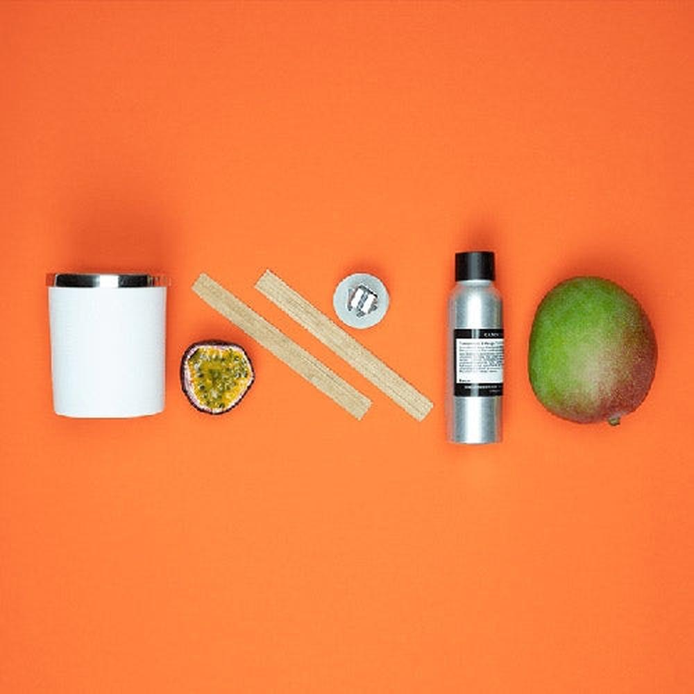 Startpakke for lysstøping med hvit beholder, treveker, pasjonsfrukt, mango og duftolje på oransje bakgrunn