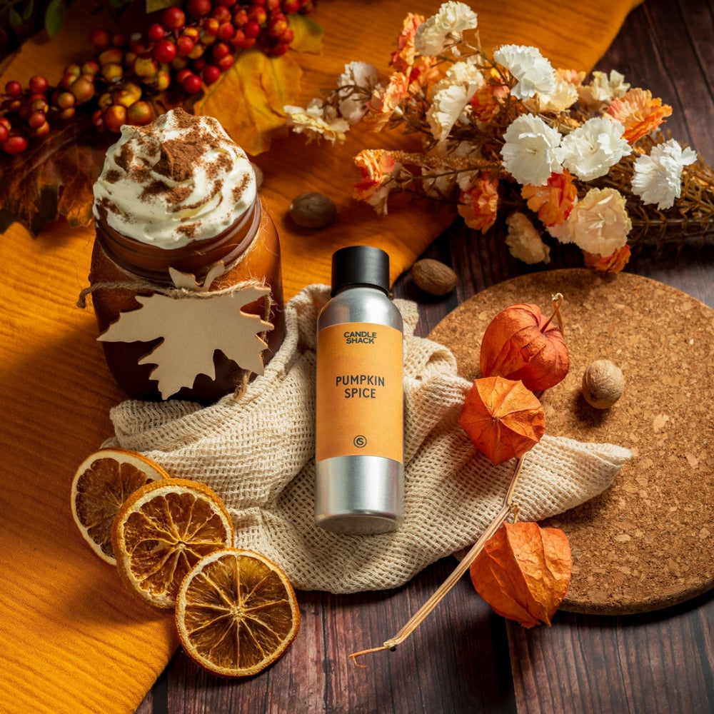 Sølvfarget flaske med Pumpkin Spice duftolje, omringet av tørkede appelsinskiver, pyntegresskar og høstdekor.