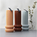 Tre romerske søylelys i soyavoks: beige, brun og lyseblå, med veker og "Handmade" tagger.