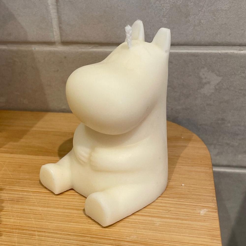 Kremhvit tegneseriefigur lys, ca 65mm høy, med veke, sittende på et trebrett